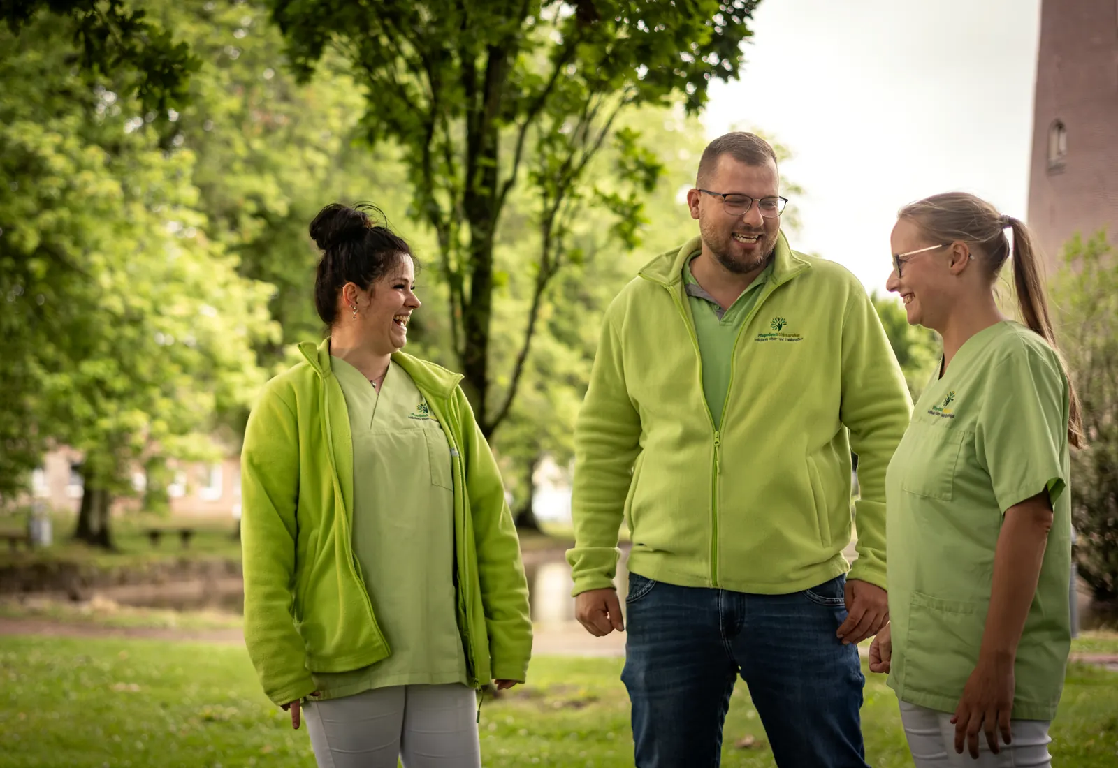 Mitarbeitende der Pflegegruppe Wilstermann lachen gemeinsam im Grünen